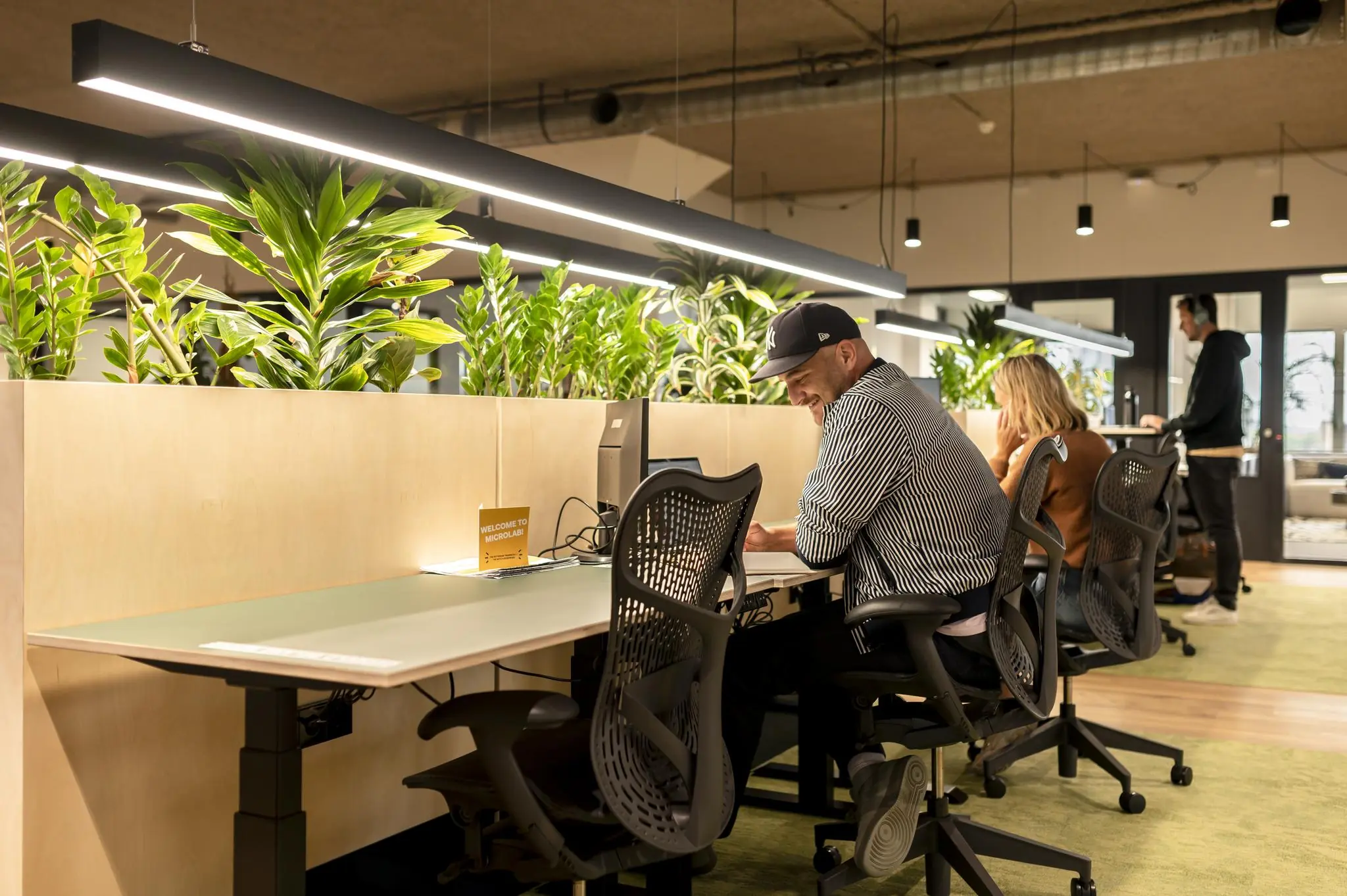 Moderne werkruimte aan de Aert van Nesstraat met mensen werkend aan bureaus, gescheiden door plantenbakken.